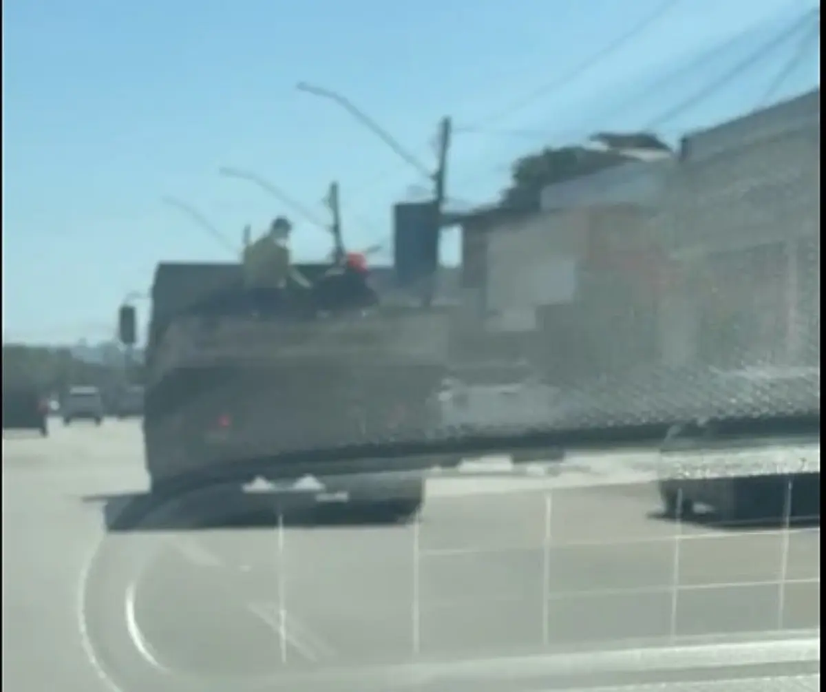 Trabalhadores são levados sobre carga de asfalto em caminhão a 60 km/h em Goiânia